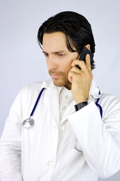 Jovem médico sério ao telefone — Fotografia de Stock