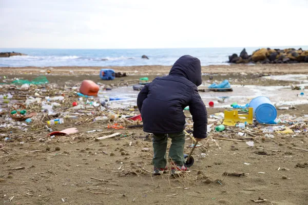 Niño jugando en la playa con suciedad desastre y peligro —  Fotos de Stock