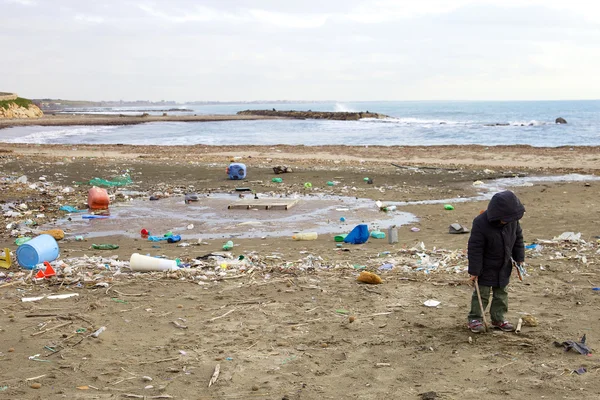 Niño que no se preocupa por la suciedad y el peligro de la playa contaminada —  Fotos de Stock