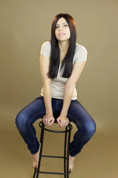 Žena sedí na židli, usmívá se ve studiu — Stock fotografie