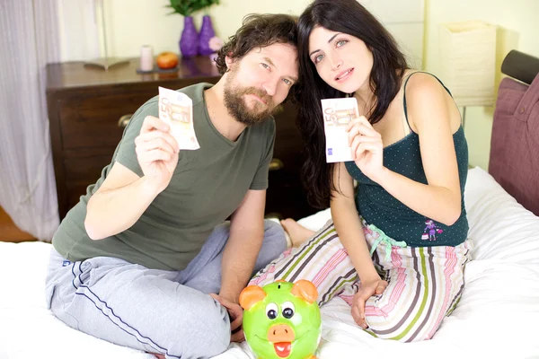 Schönes Paar zeigt Geld aus Sparschwein — Stockfoto
