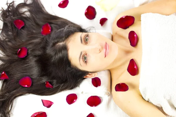 Gorgeous woman laying surrounded by rose petals — Stock Photo, Image