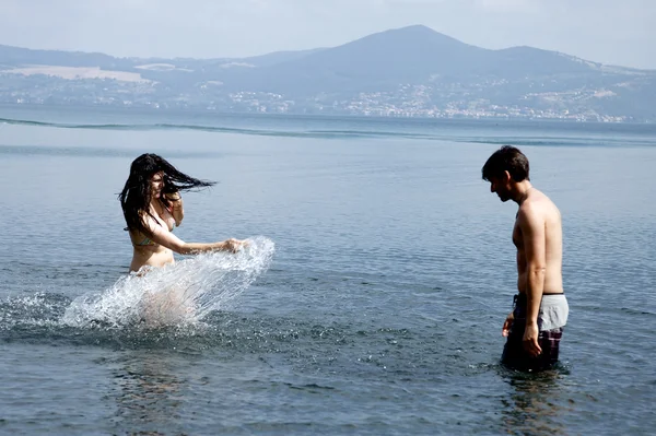 Happy woman in love splashing boyfriend in the water in vacation in Italy — Stock Photo, Image