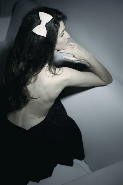 Künstlerische Aufnahme eines weiblichen Modells mit nacktem Rücken, das auf weißer Couch posiert — Stockfoto