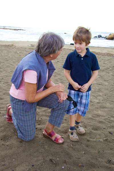 Avó feliz conversando com neto em uma praia — Fotografia de Stock