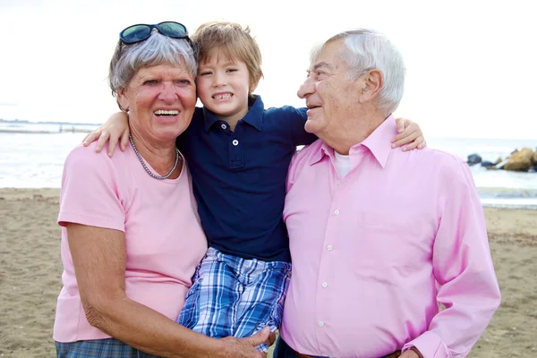 Feliz garoto bonito abraçando avós em férias — Fotografia de Stock