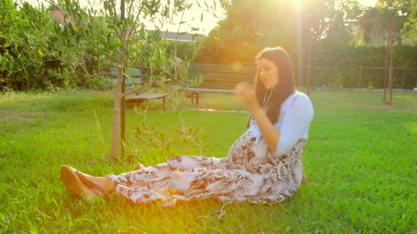 Беременная женщина отдыхает в саду — стоковое видео