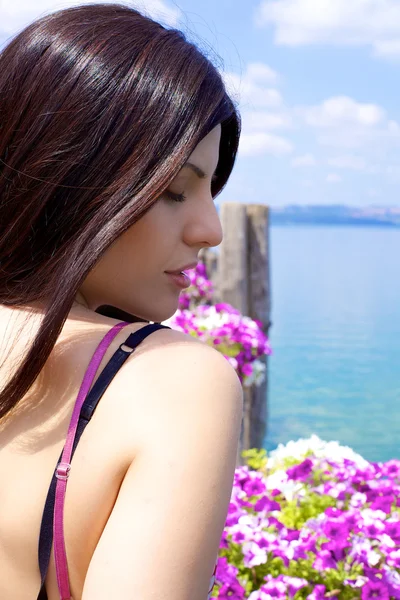 Woman relaxing in vacation in front of lake and flowers — Stock Photo, Image
