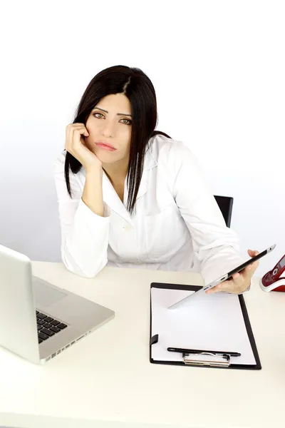 Médica aborrecida infeliz no trabalho na mesa com tecnologia — Fotografia de Stock
