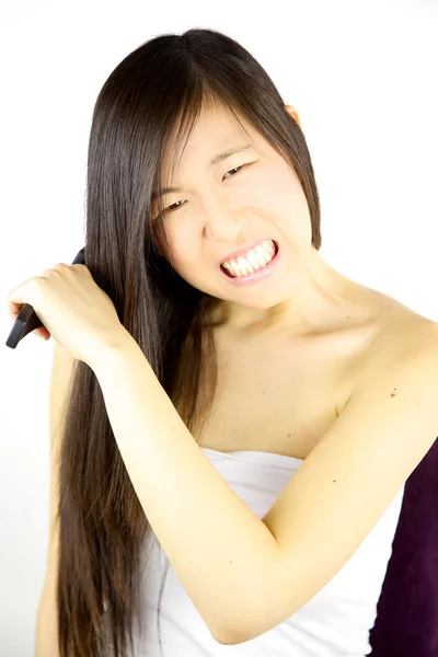 Kvinna med trassligt hår försöker borsta det — Stockfoto