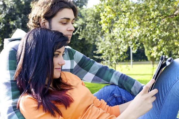 Pareja lectura tableta en el parque — Foto de Stock