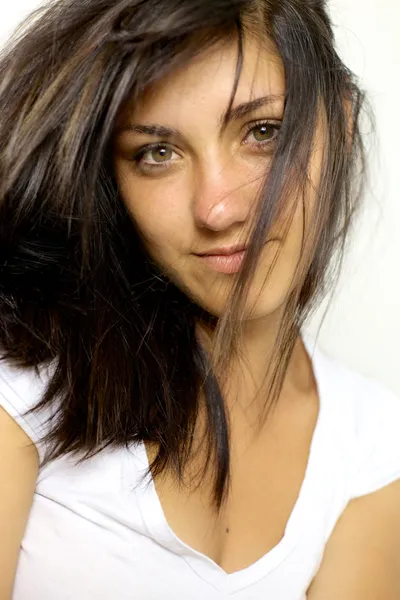 Niedliche junge Frau mit Haaren im Gesicht lächelnd — Stockfoto