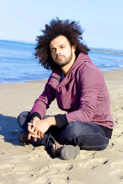 Przystojny mężczyzna siedzi na plaży myśląc poważnie — Zdjęcie stockowe