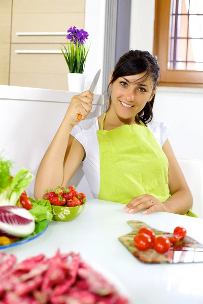 トマトをカットする準備ができての台所で幸せな若い女 ストック画像