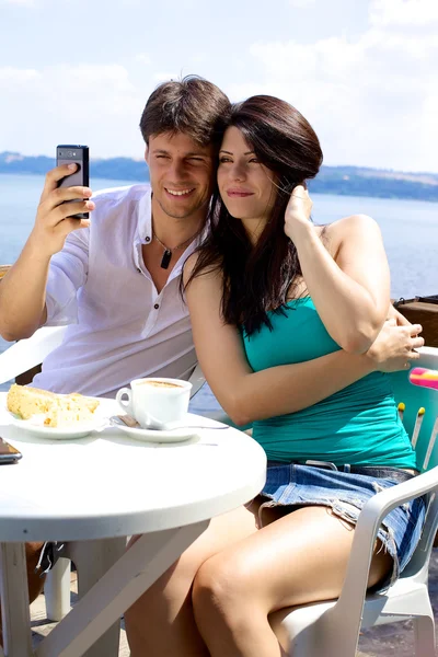 Beautiful couple taking pictures of themselves in vacation in front of lake — Stock Photo, Image