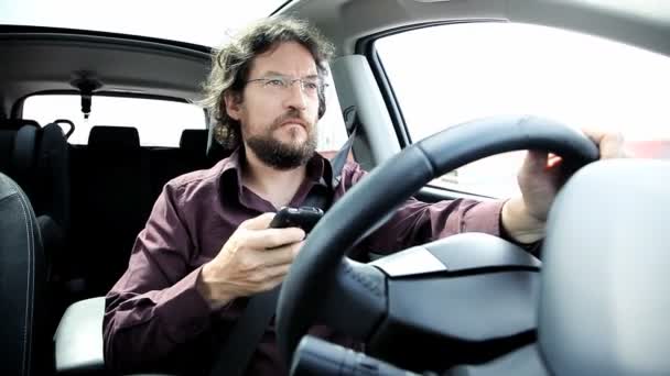 Мужчина пишет смс со смартфона за рулем — стоковое видео