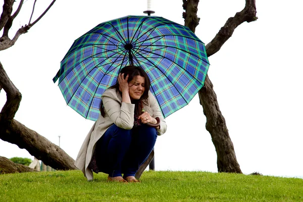 Hermosa mujer con paraguas sentado asustado de tormenta que viene — Foto de Stock