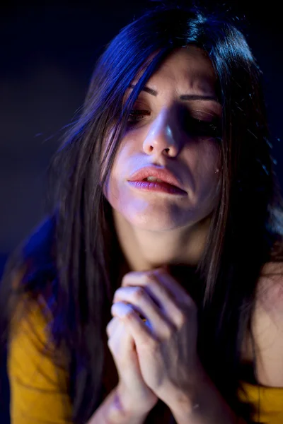 Sad woman with bruises crying in darkness praying — Stock Photo, Image