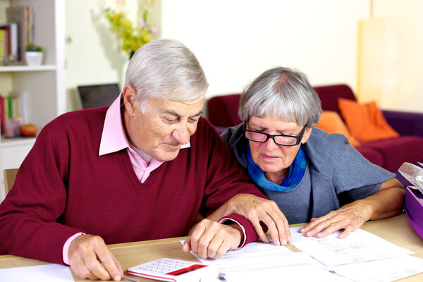 Happy senior couple at home calculating debt