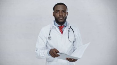 Afrikalı Amerikalı doktor, gri üzerine izole edilmiş belgelerle klasörü tutuyor.