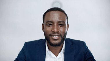 Neşeli Afro-Amerikan iş adamı gri kameraya bakıyor.