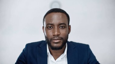 Afrikalı Amerikalı iş adamı gri kameraya bakıyor.