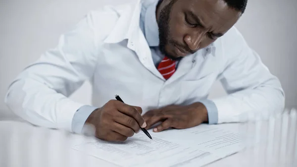 Zaměřený Africký Americký Lékař Bílém Plášti Podepisující Dokumenty Klinice — Stock fotografie
