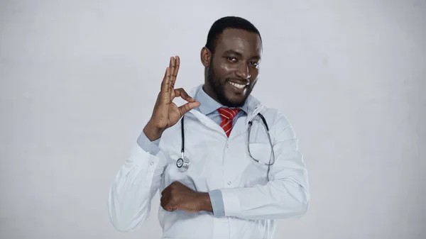 Wesoły African Amerykański Lekarz Pokazując Znak Izolowany Szarości — Zdjęcie stockowe