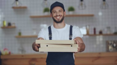 Evdeki bulanık teslimatçının ellerinde pizza kutuları. 