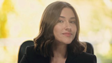 Pozitif esmer iş kadını ofisteki kameraya bakıyor