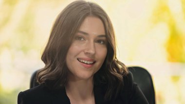 Genç ve mutlu iş kadını ofiste kameraya gülümsüyor.