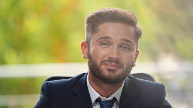 Genç iş adamı ofiste kameraya gülümserken giyinir.