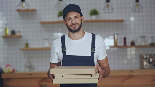 Young delivery man holding pizza boxes at home 