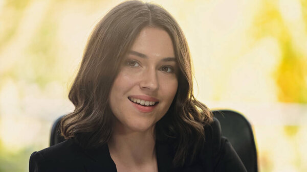 молодая и счастливая деловая женщина улыбается перед камерой в офисе