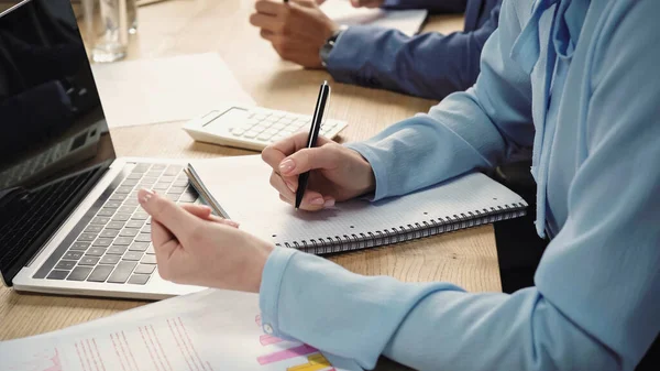 Vista Recortada Mujer Negocios Escribiendo Cuaderno Cerca Computadora Portátil Con —  Fotos de Stock