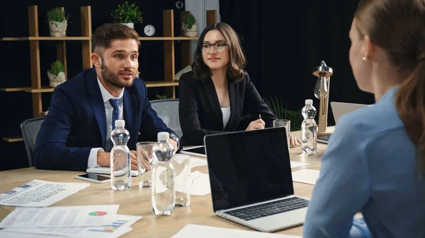 Jóvenes Gerentes Sentados Cerca Borrosa Colega Portátil Con Pantalla Blanco — Foto de Stock