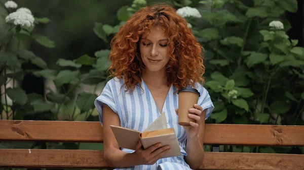 Приятно Рыжая Женщина Платье Чтение Книги Проведение Бумажной Чашки Сидя — стоковое фото