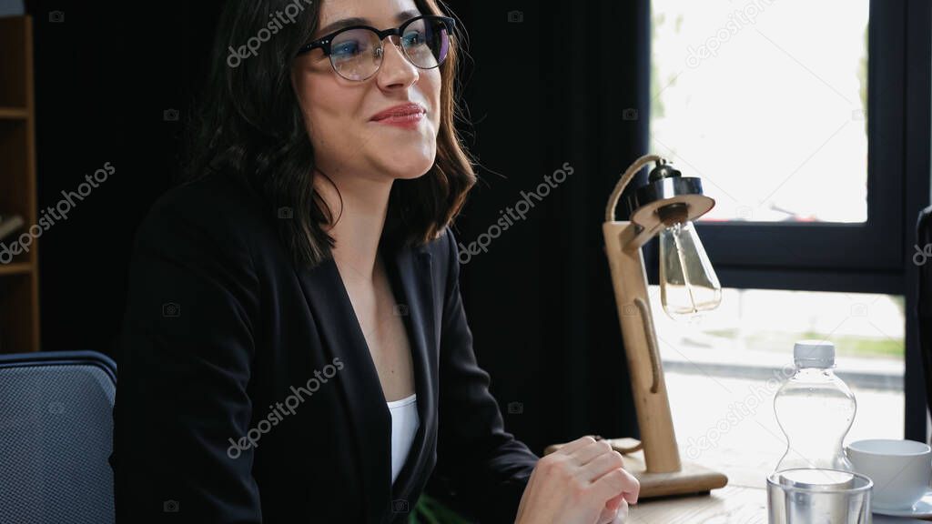 young businesswoman in eyeglasses smiling in meeting room