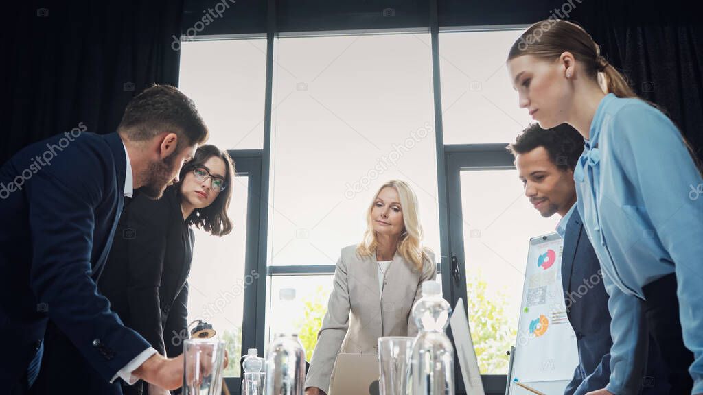 low angle view of interracial business people standing during discussion in meeting room
