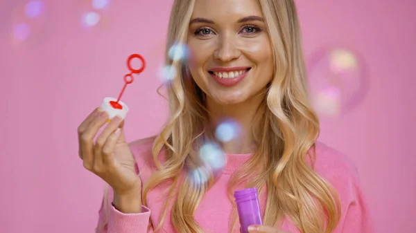 Positiv Blond Kvinna Håller Trollspö Nära Såpbubblor Isolerad Rosa — Stockfoto