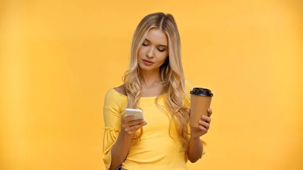 Femme Blonde Utilisant Smartphone Tenant Tasse Papier Isolé Sur Jaune — Photo