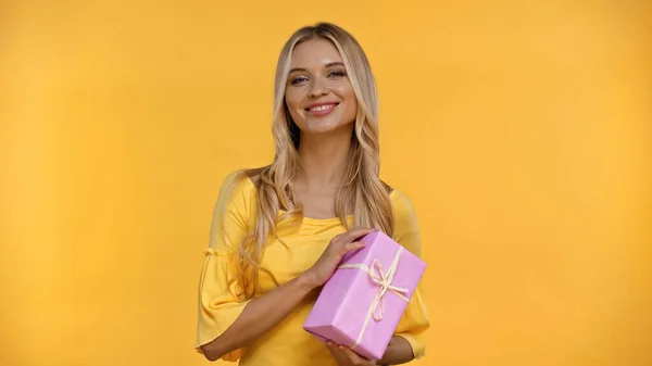 Glada Blonda Kvinna Tittar Kameran Och Håller Presentförpackning Isolerad Gul — Stockfoto