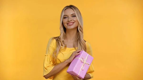 Mujer Rubia Alegre Mirando Cámara Sosteniendo Caja Regalo Aislado Amarillo —  Fotos de Stock