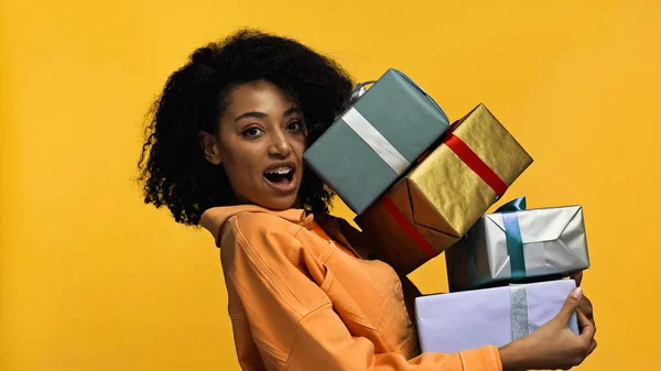 Förvånad Afrikansk Amerikansk Kvinna Med Hängslen Håller Presentförpackning Isolerad Gul — Stockfoto