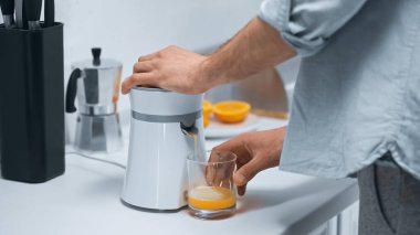 partial view of man preparing fresh orange juice in kitchen clipart
