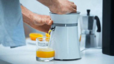 cropped view of man preparing fresh orange juice for breakfast in kitchen clipart