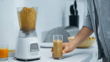 Erkeğin taze meyve püresi ve elektrikli blender bardağının yanındaki kısmi görüntüsü