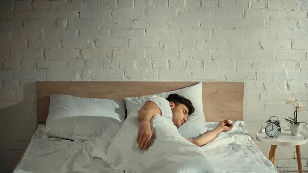 Adam Klasik Çalar Saatin Yanında Beyaz Bir Yatakta Uyuyor Komodinin — Stok fotoğraf