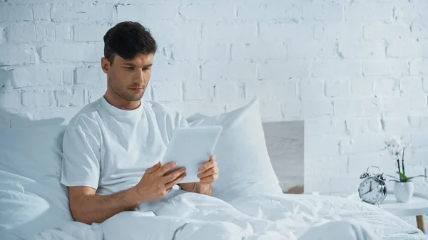 Man Sitter Sängen Nära Vintage Väckarklocka Och Använda Digital Tablett — Stockfoto