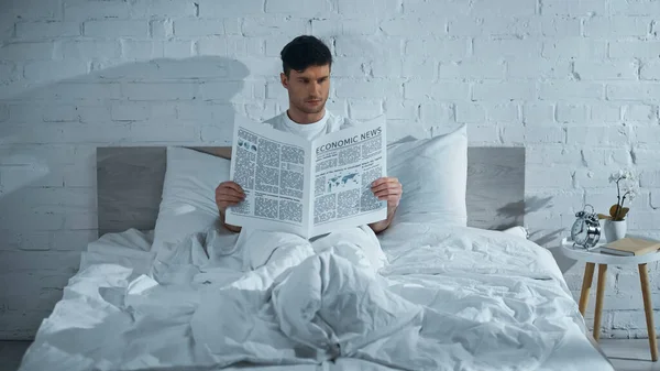 Homem Lendo Jornal Enquanto Sentado Cama Sob Cobertor Branco — Fotografia de Stock